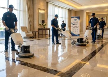 فريق عمل متخصص من شركة جلي وتلميع الرخام في ابوظبي يستخدم آلات جلي حديثة لتلميع أرضية رخامية واسعة داخل بهو فندق فاخر، وتظهر الأرضية لامعة وتعكس الإضاءة.