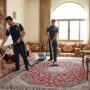 فريق متخصص من شركة تنظيف مجالس في عجمان يستخدم أجهزة التنظيف بالبخار والمكانس الكهربائية لتعقيم الكنب والسجاد في مجلس عربي تقليدي.