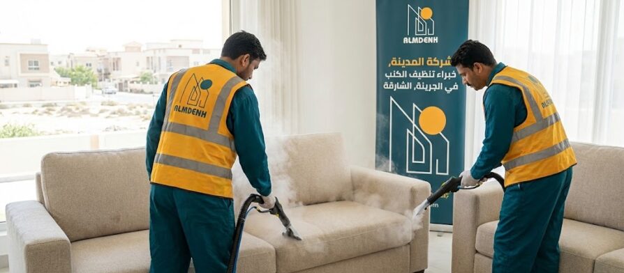 النص البديل عمال شركة المدينة، بصفتها شركة تنظيف كنب في الجرينة بالشارقة، يقومون بتنظيف كنب فاتح اللون باستخدام تقنية البخار داخل فيلا، مع ظهور لافتة إعلانية تحمل الهوية البصرية للشركة.