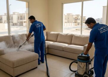 فريق عمل متخصص يقوم بغسيل وتعقيم طقم كنب بالبخار داخل فيلا سكنية حديثة، مما يبرز خدمات أفضل شركة تنظيف كنب في العامرة بعجمان.