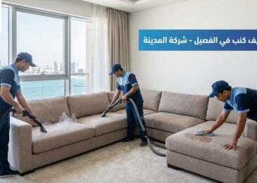 فريق عمل متخصص من شركة المدينة، وهي شركة تنظيف كنب في الفصيل بالفجيرة، يقوم بعملية تنظيف وغسيل شامل لكنب زاوية كبير باستخدام أجهزة البخار والشفط والمسح اليدوي داخل شقة ذات إطلالة بحرية، مع ظهور شعار الشركة ونص يوضح الخدمة.