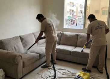 فريق شركة المدينة يقوم بتنظيف كنب بالبخار داخل شقة سكنية تطل على شارع حيوي، موضحاً كفاءة أفضل شركة تنظيف كنب في الكرامة في إزالة الغبار والروائح.