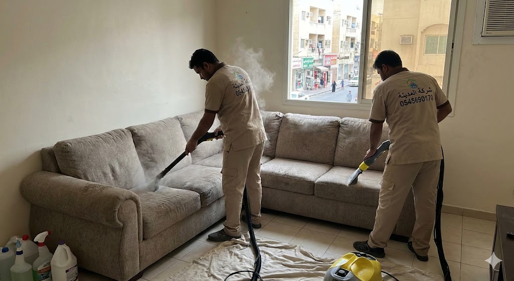 فريق شركة المدينة يقوم بتنظيف كنب بالبخار داخل شقة سكنية تطل على شارع حيوي، موضحاً كفاءة أفضل شركة تنظيف كنب في الكرامة في إزالة الغبار والروائح.