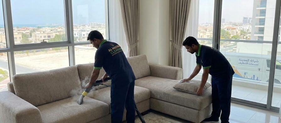 فريق عمل شركة المدينة أثناء تنظيف وغسيل الكنب بالبخار، كأفضل شركة تنظيف كنب في الممر.