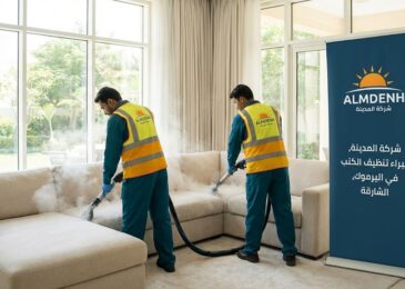 عمال شركة المدينة، بصفتها شركة تنظيف كنب في اليرموك بالشارقة، يغسلون كنب زاوية فاتح اللون بالبخار بجوار لافتة تحمل شعار الشركة.