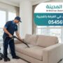 فني محترف يستخدم جهاز الغسيل والشفط العميق لتنظيف أريكة قماشية حديثة، يمثل خدمات أفضل شركة تنظيف كنب في الغرفة بإمارة الفجيرة.