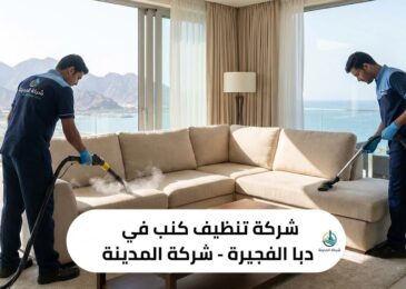 فريق عمل متخصص من شركة المدينة، وهي شركة تنظيف كنب في دبا الفجيرة، يستخدم أحدث أجهزة التنظيف بالبخار لغسيل كنب بيج كبير في غرفة معيشة فاخرة تطل على البحر والجبال، مع ظهور شعار الشركة ونص توضيحي للخدمة.