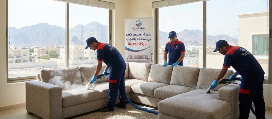 فريق عمل شركة المدينة، بصفتها شركة تنظيف كنب في سكمكم، يستخدم أجهزة البخار لتنظيف كنب كبير في غرفة مطلة على الجبال، مع وجود لافتة توضح الخدمة.