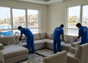 فريق عمل متخصص من شركة التلة يقوم بخدمة غسيل وتعقيم طقم كنب بالبخار داخل منزل، مما يبرز خدمات أفضل شركة تنظيف كنب في التلة بعجمان.