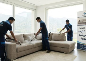 فريق عمل شركة المدينة، بصفتها شركة تنظيف كنب في مريشيد، يستخدم أجهزة البخار لتنظيف كنب كبير في غرفة مطلة على الجبال، مع وجود لافتة توضح الخدمة.