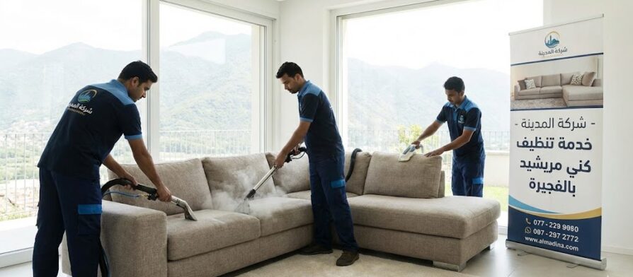 فريق عمل شركة المدينة، بصفتها شركة تنظيف كنب في مريشيد، يستخدم أجهزة البخار لتنظيف كنب كبير في غرفة مطلة على الجبال، مع وجود لافتة توضح الخدمة.