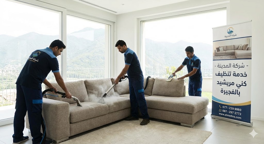 فريق عمل شركة المدينة، بصفتها شركة تنظيف كنب في مريشيد، يستخدم أجهزة البخار لتنظيف كنب كبير في غرفة مطلة على الجبال، مع وجود لافتة توضح الخدمة.