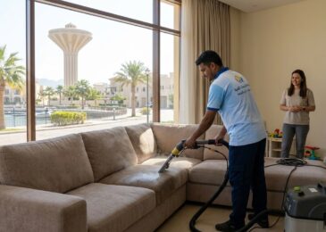 عامل محترف من شركة تنظيف كنب في الخزان ينجز أعمال غسيل وتعقيم أريكة بالبخار داخل منزل سكني ذو إطلالة خارجية.