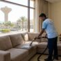 عامل محترف من شركة تنظيف كنب في الخزان ينجز أعمال غسيل وتعقيم أريكة بالبخار داخل منزل سكني ذو إطلالة خارجية.