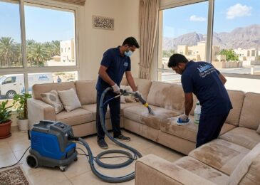 فريق عمل محترف من شركة تنظيف كنب في الدقداقة يقوم بغسيل وتعقيم الكنب بالبخار داخل مجلس إماراتي ذي إطلالة خارجية.