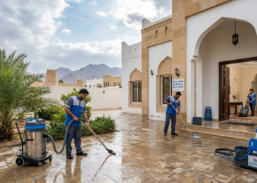 عمال شركة المدينة يستخدمون معدات متطورة لشفط المياه وتجفيف الأرضيات أثناء تنفيذ أعمال تنظيف منازل في العين بعد الامطار في فناء فيلا تقليدية.